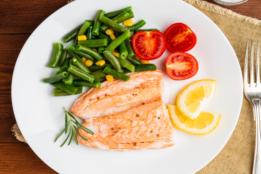 Une assiette remplie de 300g de repas dont peu de crudité et du saumon avec du citron