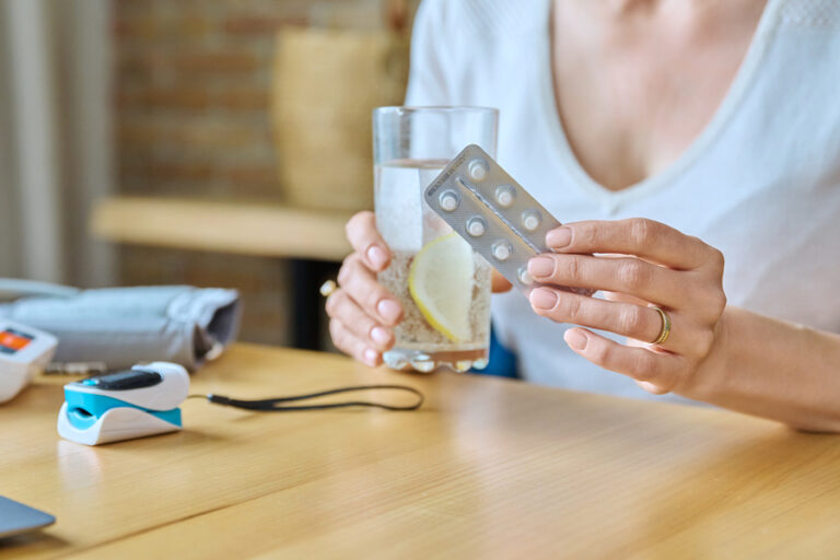 Une femme prenant des pilules avec un verre d'eau après le retrait de son implant.