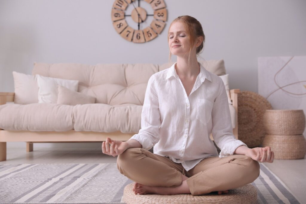 Une jeune femme assise sur un tapis en osier en faisant de la méditation