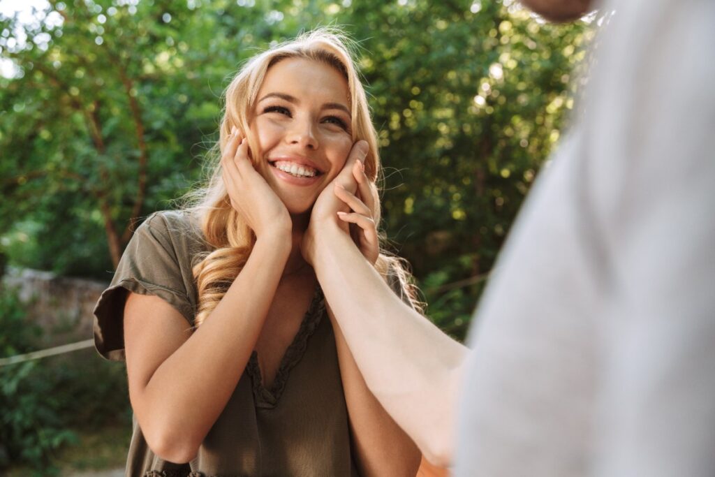 Une femme souriante devant un homme qui touche son visage