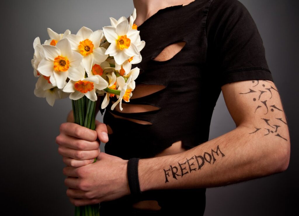 Une personne tenant des fleurs avec des tatouages sur le bras