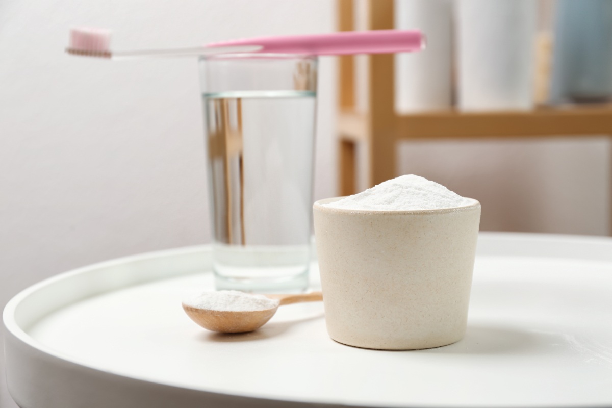 Un bol rempli de bicarbonate de soude avec une brosse à dent sur un verre d'eau
