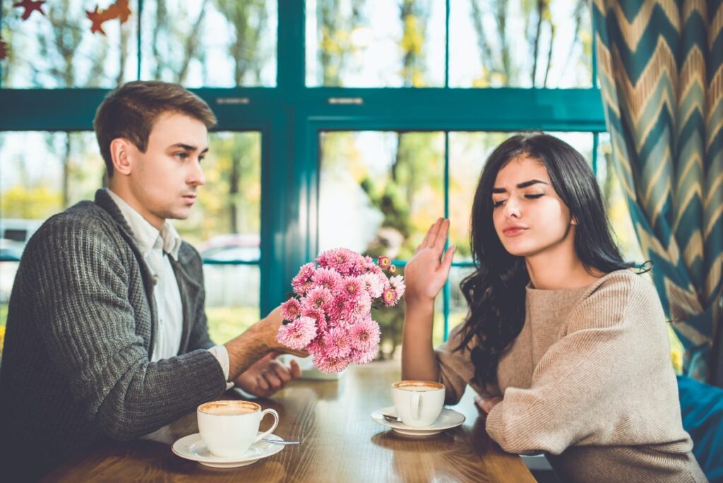 Une femme qui refuse de prendre les fleurs que l'homme lui offre