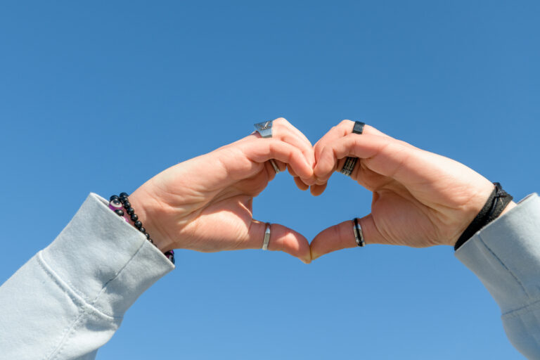 Main formant un coeur sous le ciel bleu