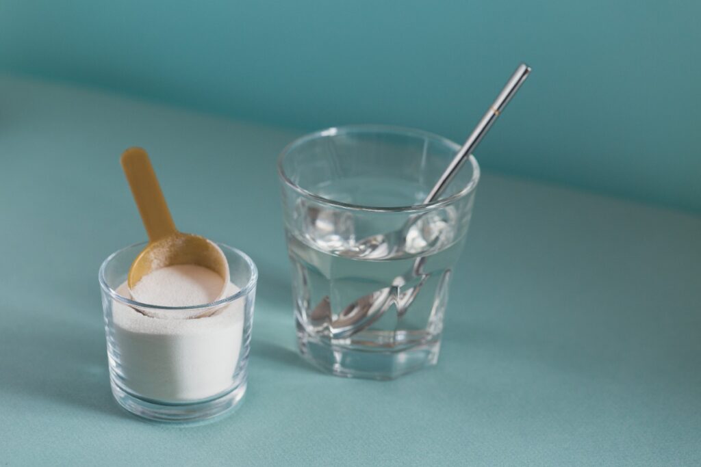 Un verre d'eau et un verre rempli de bicarbonate de soude avec une cuillère en bois