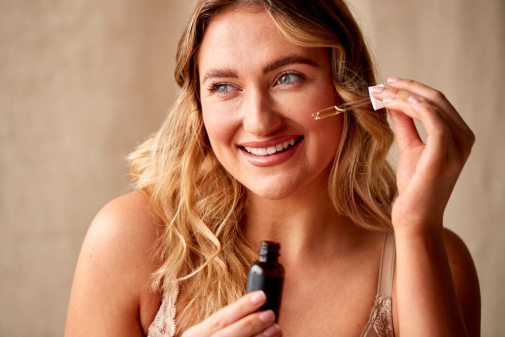 Une femme heureuse en mettant du sérum sur le visage