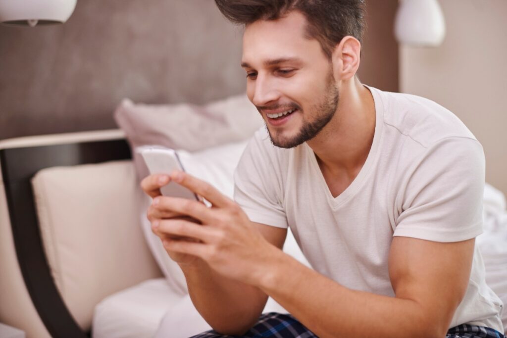 Un homme souriant utilisant un téléphone