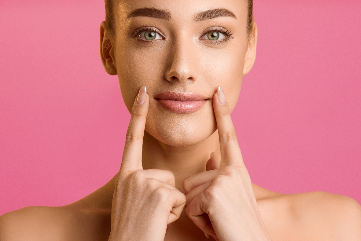 Une belle femme souriante mettant les mains sur la joue