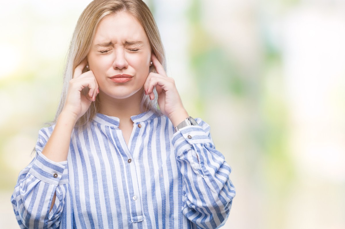 Une femme se couvrant les oreilles avec les mains