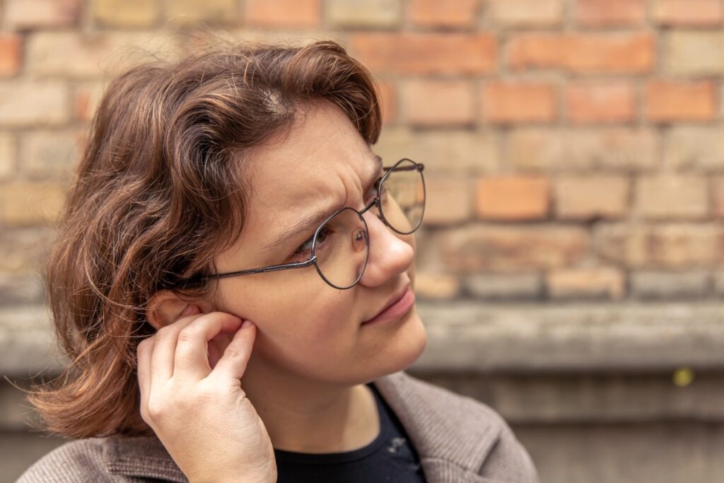 Une femme portant une lunette et touchant l'oreille